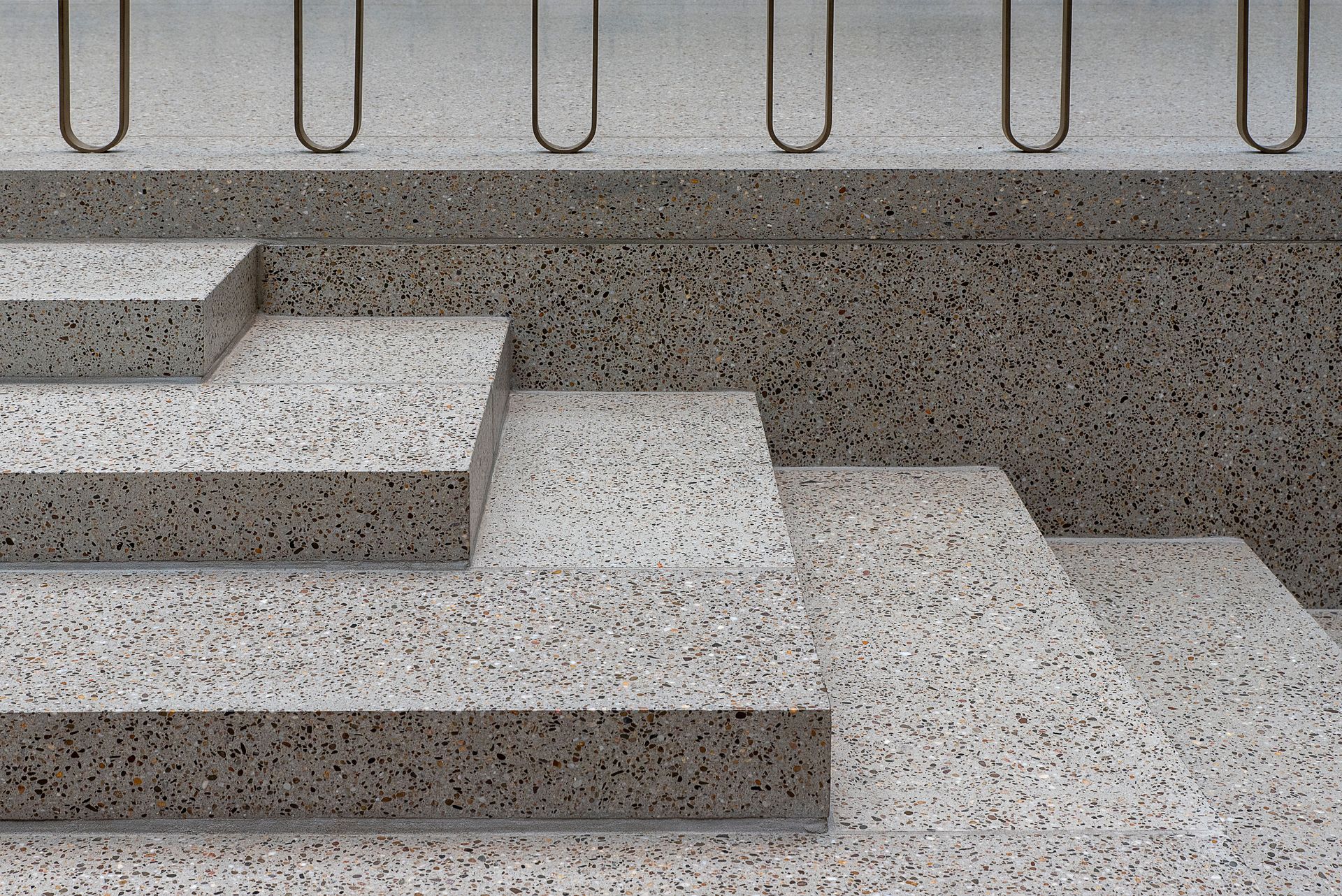 Minimalist concrete staircase featuring terrazzo texture and sleek metal railings.